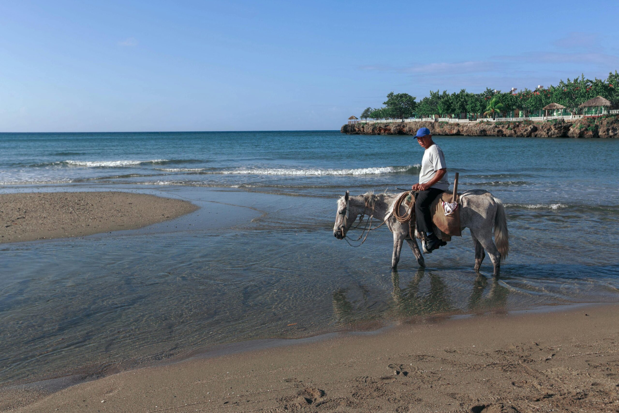 A man riding a horse along the seaside on a sunny day, capturing a relaxing coastal scene.