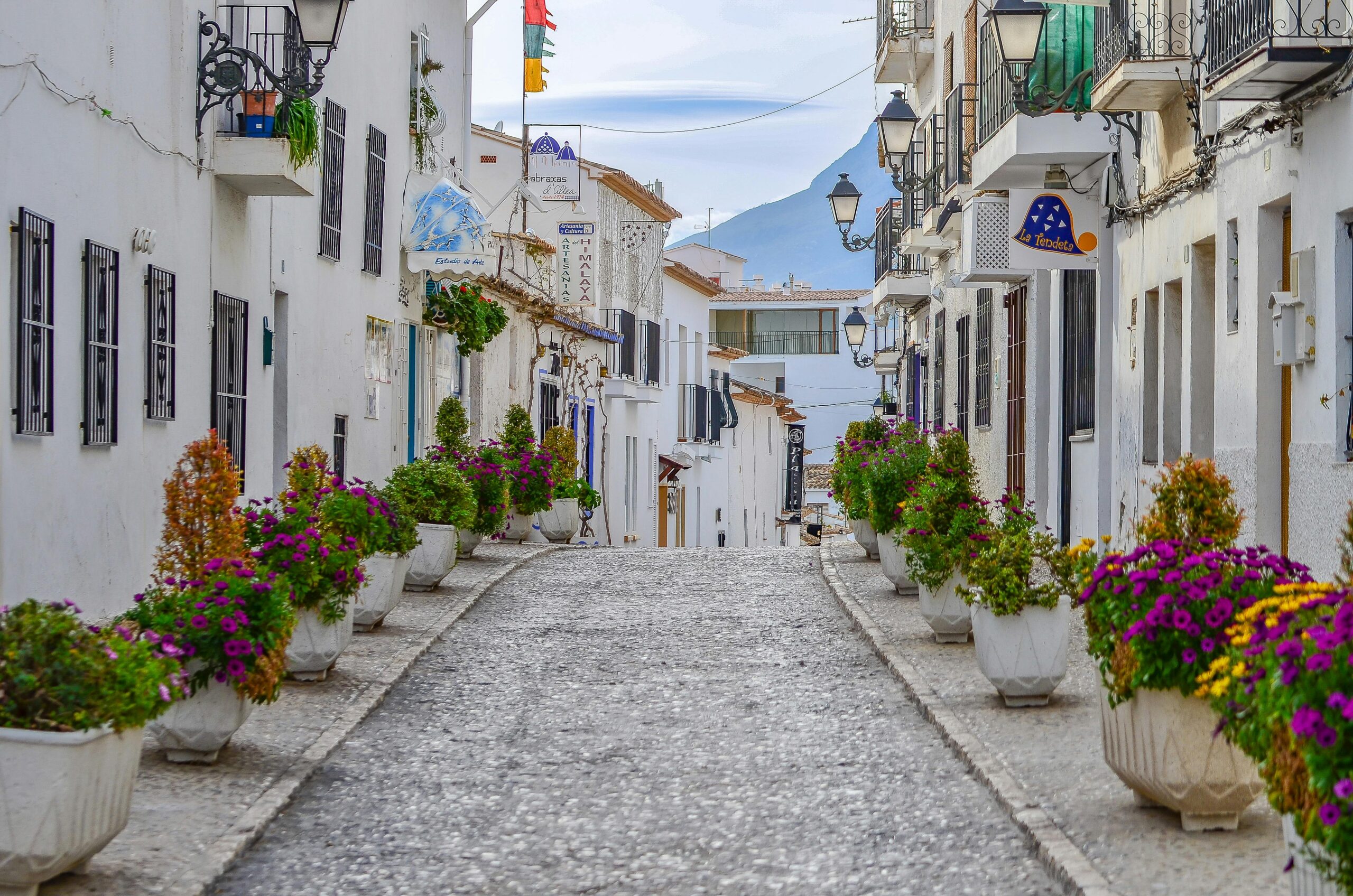 Picturesque alley in Altea, Spain, adorned with vibrant flowers and whitewashed buildings.